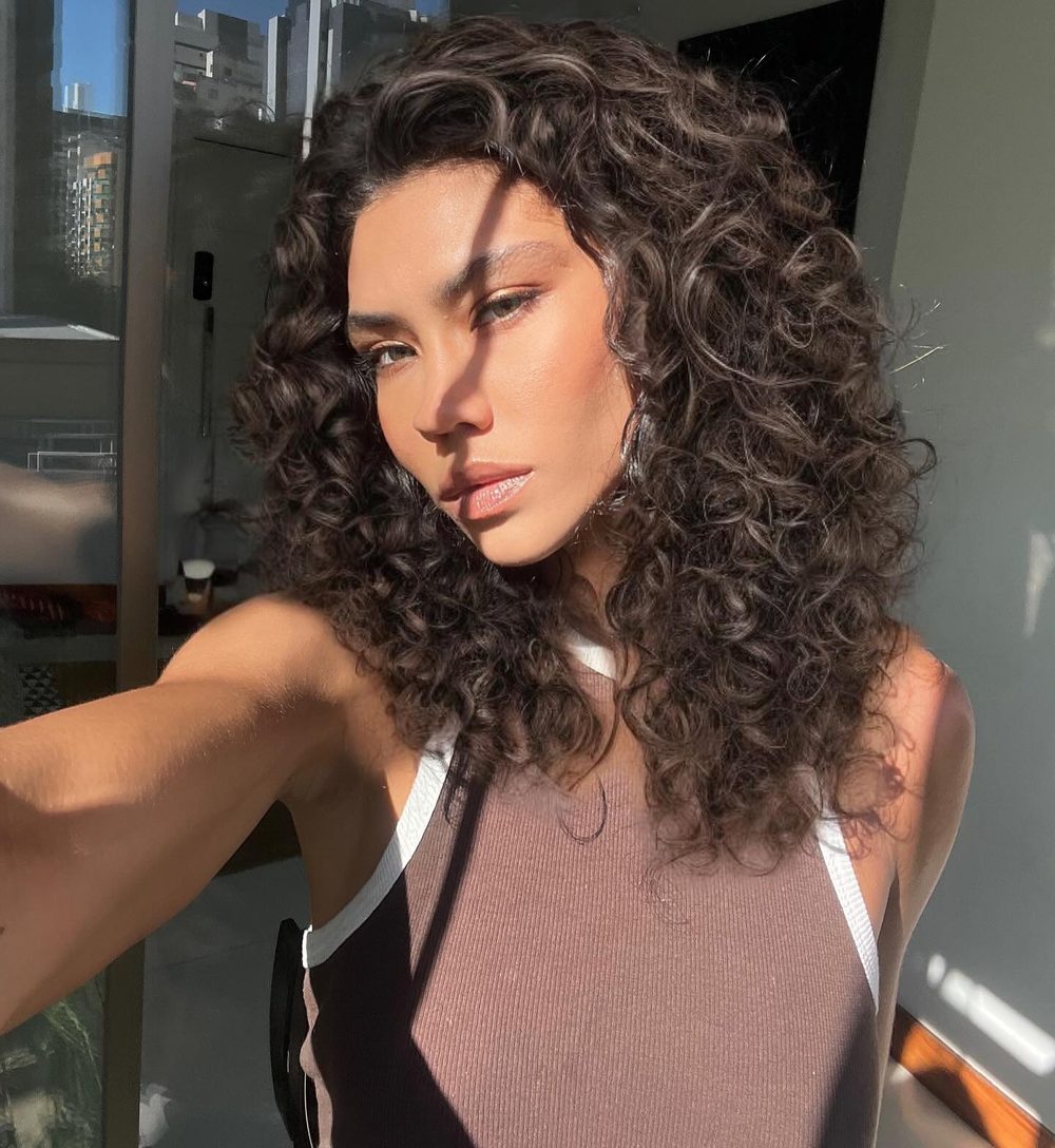Julia Pedroni com cabelo cacheado à luz do sol